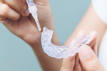 patient holding clear plastic aligner | dentist mccrae