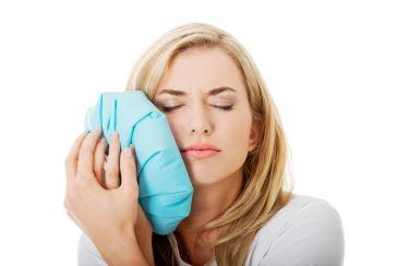 woman holding ice to jaw | emergency dentist mccrae